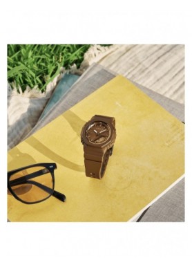 G-SHOCK GMA-P2110B-5AER marrone scuro su quaderni accanto a occhiali da sole